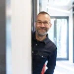 Lächelnder Mensch, der aus dem Türrahmen schaut