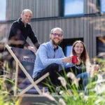 3 Personen auf einer Terrasse, die lächelnd in die Kamera schauen